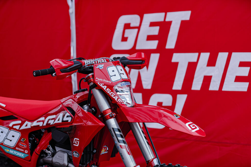 Andrea Verona's red enduro GP bike in front of a red wall that reads 'Get on the gas!'
